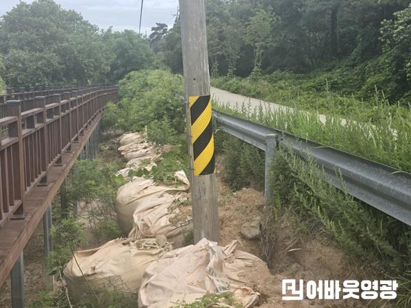 영광군 불갑저수지 ‘물멍쉼터’로 이어지는 데크길 인근. 가드레일 아래 토사가 심하게 쓸려 내려갔고, 전신주는 한쪽으로 기울어진 채 방치돼 있어 안전사고 우려가 제기된다..jpg